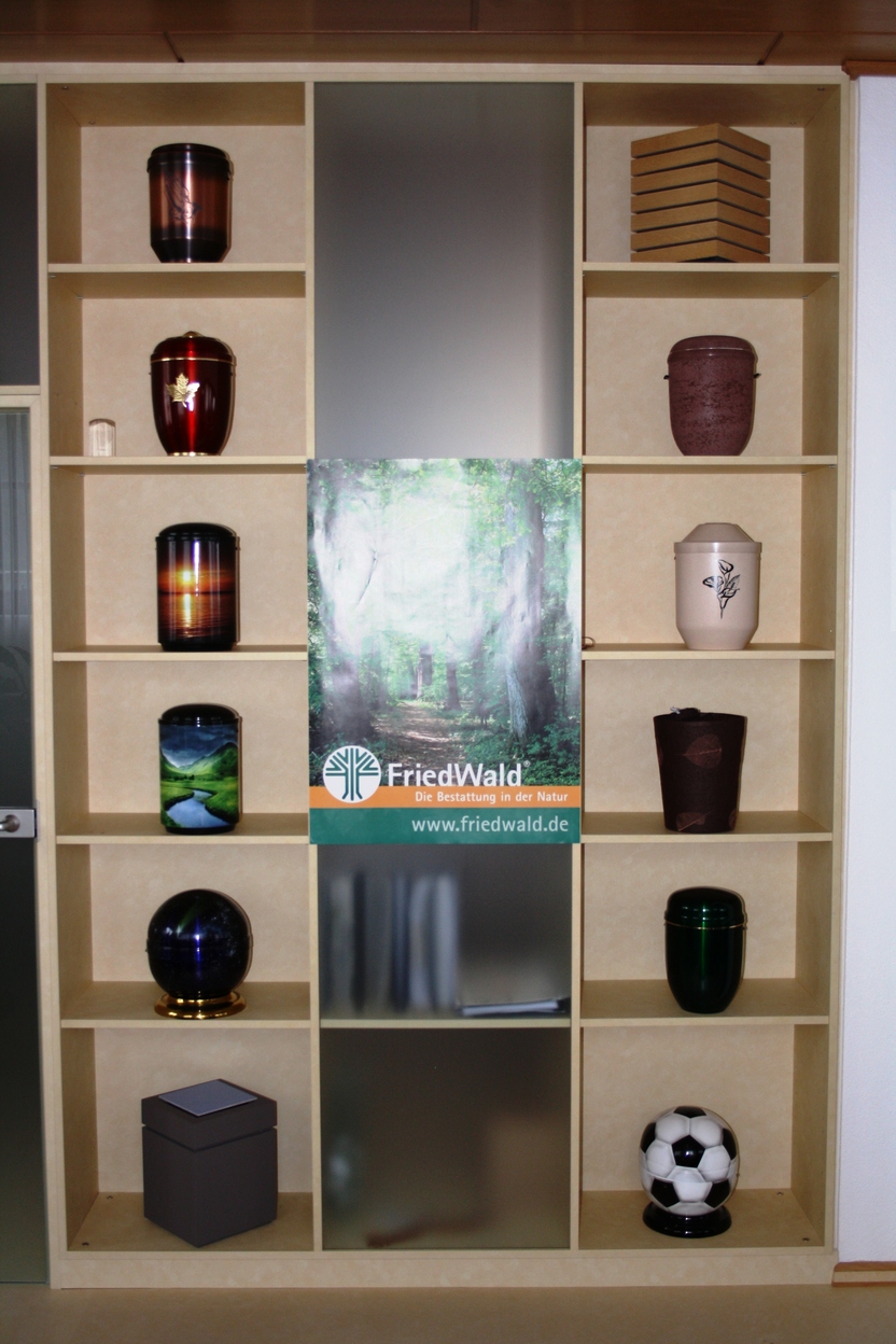 Regal mit verschiedenen Vasen, einem Fu&szlig;ball und einem Werbebanner in der Mitte, auf hellbraunem Hintergrund.