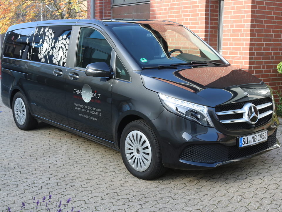 Schwarzer Mercedes-Van mit auff&auml;lliger Beschriftung, geparkt auf einer gepflasterten Einfahrt.