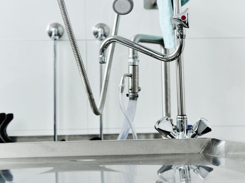 Nahaufnahme eines modernen K&uuml;chensp&uuml;lbeckens mit Wasserhahn und reflektierender Oberfl&auml;che.