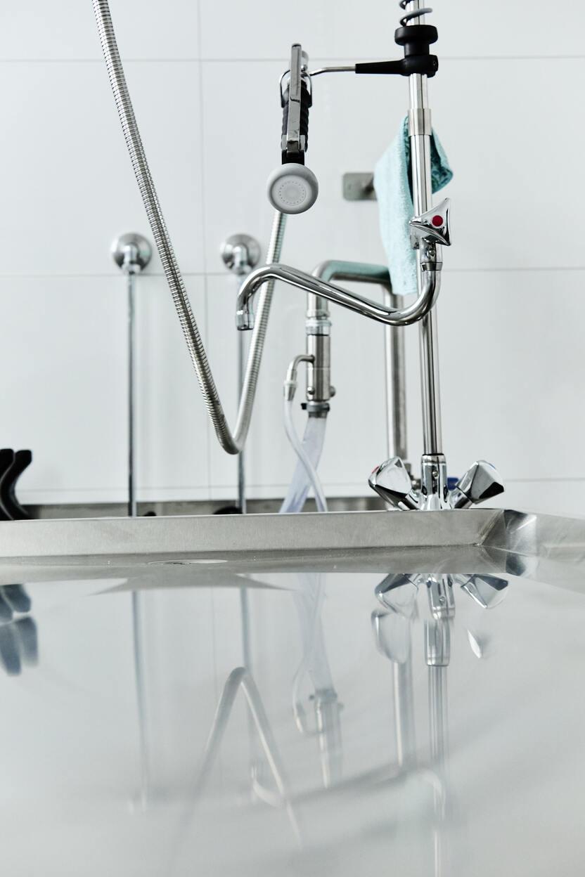 Nahaufnahme eines modernen Küchenspülbeckens mit Wasserhahn und reflektierender Oberfläche.